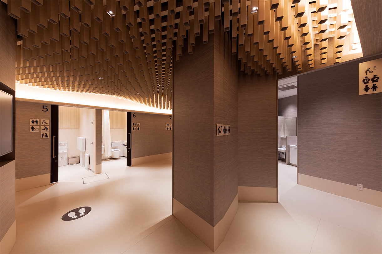 選べるトイレ トイレ入口 全景 右にベビーケアルーム、左に個室群。さまざまな用途を示したピクトグラムが掲示されている。写真/傍島利浩