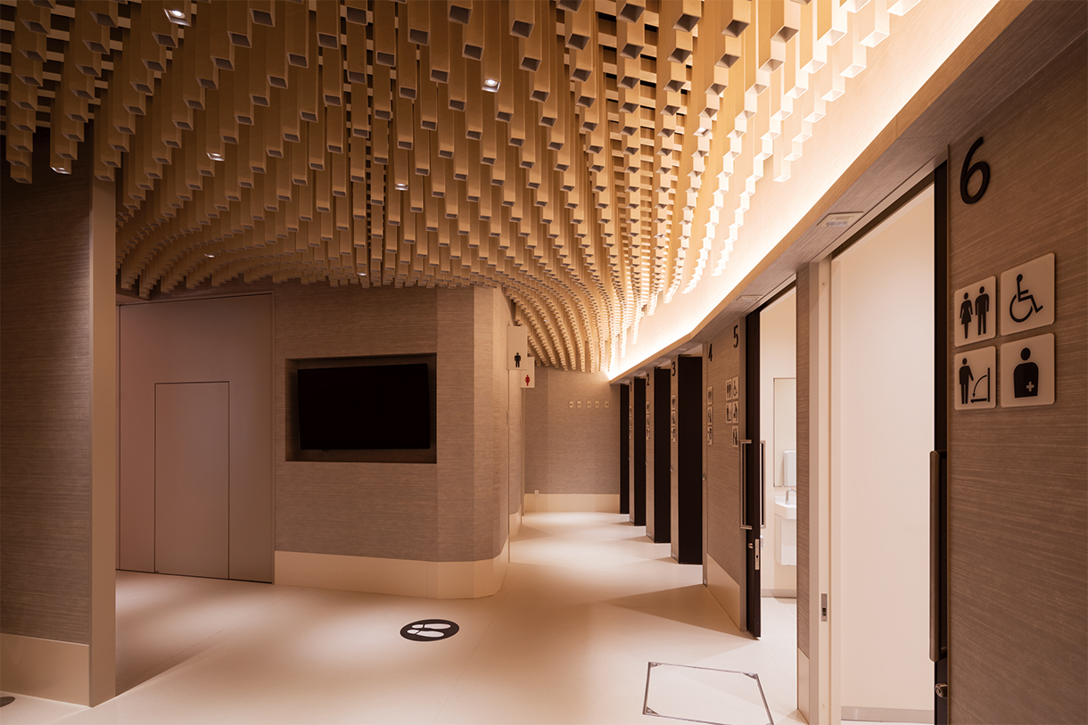 紙の筒がうねる天井 全景 サイネージの画面に個室の使用状況が表示され、列の先頭を示すストップマークからは、個室の空き状況を見渡すことができる。写真/傍島利浩