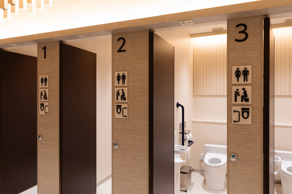 紙の筒がうねる天井 ピクトグラム 個室前のピクトグラム。左右どちらに手すりが付いているのかもわかる。写真/傍島利浩