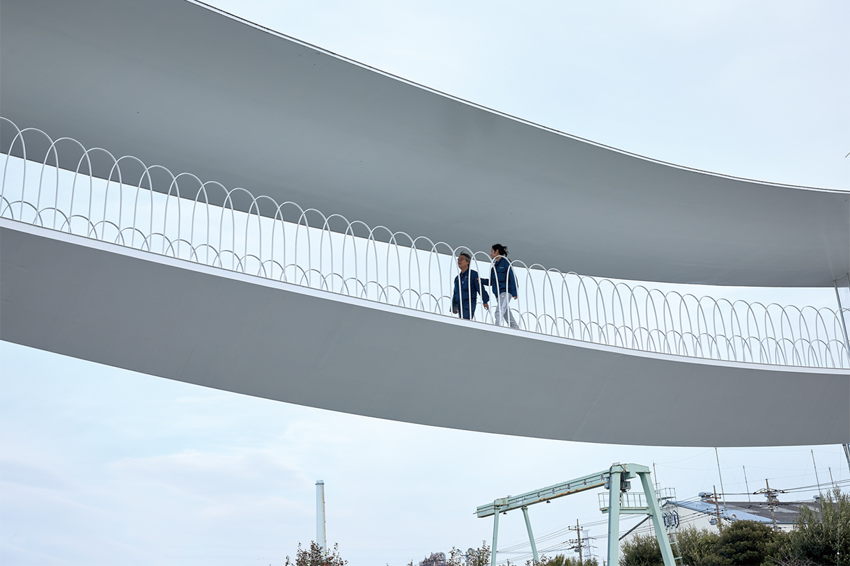 地上からブリッジを見上げる。白い鯨のような造形。写真/川辺明伸